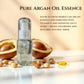 Bottle of pure argan oil essence with argan kernels and seeds on a light background