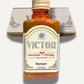Close-up of Roomsium Victor Shampoo bottle in front of amenities box on light background
